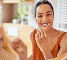 Woman smiling while brushing her teeth