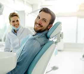 Dentist and patient smiling in treatment room