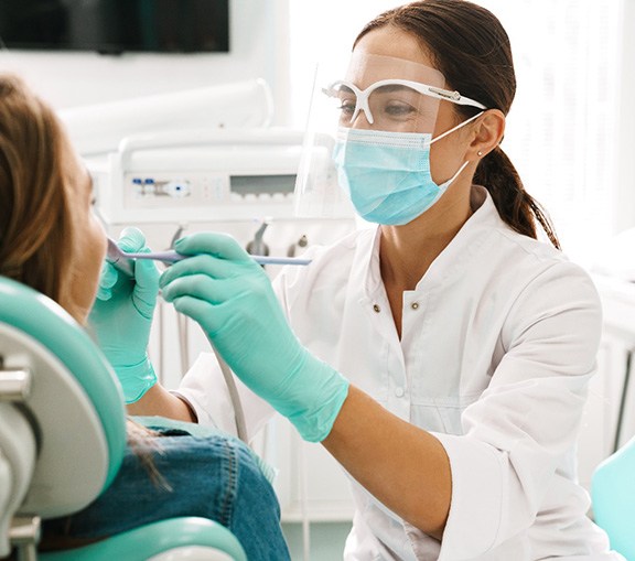 Smiling dentist examining patient's teeth