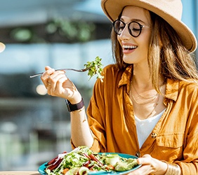 Woman smiling while eating salad outside